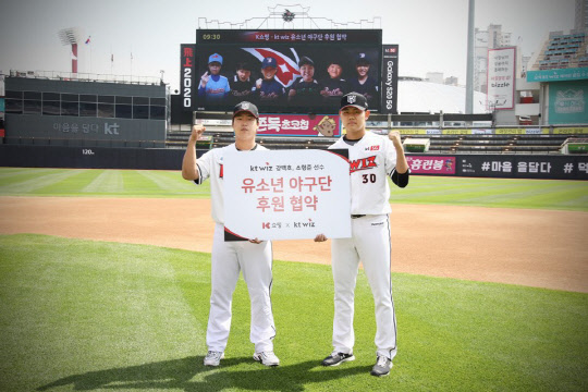 지난 27일 K쇼핑을 운영하는 KTH와 kt wiz가 공동 사회공헌 및 홍보마케팅 협력을 위한 업무협약을 체결했다. 사진은 업무협약 체결 후 kt wiz 강백호(왼쪽), 소형준 선수가 후원하는 베스트원 야구단 및 멘토리 야구단 대표학생들과 함께 비대면 기념사진을 촬영하는 모습. [KTH 제공]